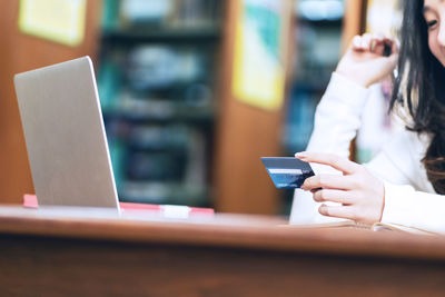 Midsection of woman using smart phone on table