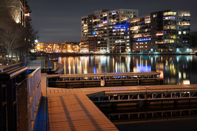 Illuminated bridge over canal by buildings in city at night