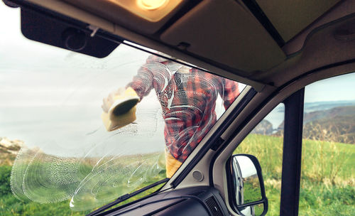 Man cleaning camper van windshield outdoor