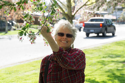 Portrait of smiling senior woman holding branch