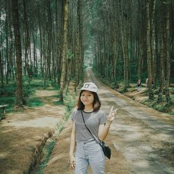 Portrait of smiling young woman gesturing while standing in forest