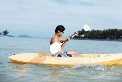 Rear view of man kayaking in lake