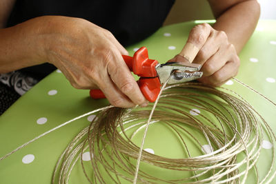 Midsection of woman cutting cable on table