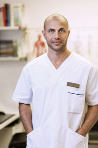 Portrait of confident orthopedic surgeon standing with hands in pockets in clinic