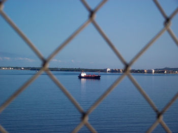 Scenic view of sea against sky seen through chainlink fence