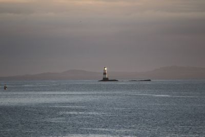 Lighthouse by sea against sky