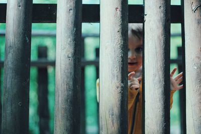 Boy seen through wooden railing on footbridge