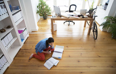 Woman sitting on the floor reading documents barefoot