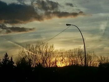 Silhouette of bare trees against sky at sunset