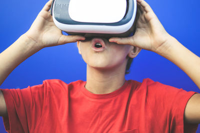 Boy wearing virtual reality simulator against blue background