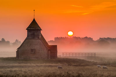 Church on field against orange sky