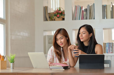 Young woman using phone while sitting on table