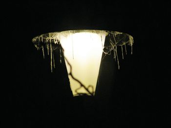 Low angle view of illuminated lighting equipment against black background