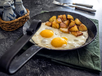 High angle view of fried egg with potatoes in frying pan on table