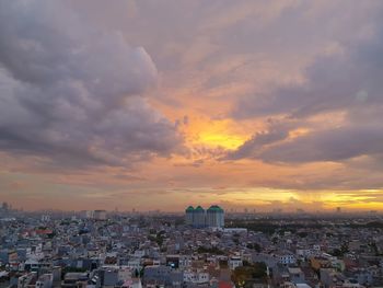 High angle view of city against cloudy sky during sunset