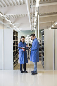 Full length of electricians reading file together at industry