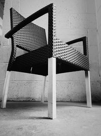 Low angle view of whicker chair against wall