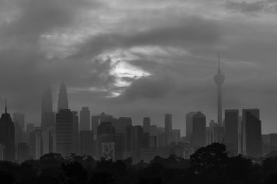 Skyscrapers in city against cloudy sky