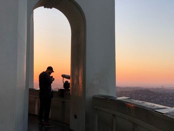 Silhouette man photographing sea against clear sky during sunset