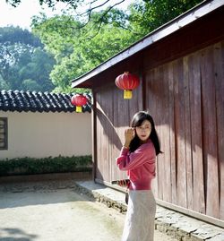 Portrait of young woman standing against trees