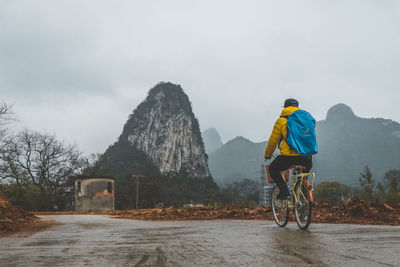 Rear view of man riding bicycle on road