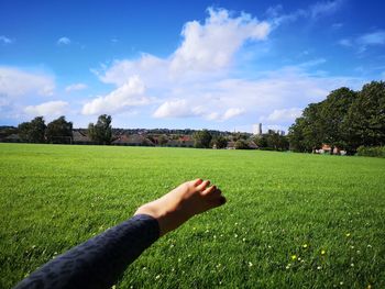 Close up of young woman leg on field against sky