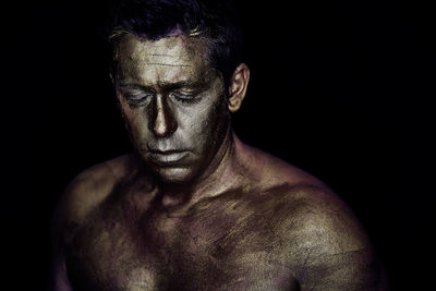 Shirtless man with face paint against black background