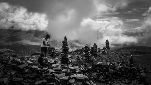 Rear view of man standing on rock against sky