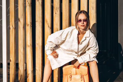 Portrait of young woman sitting against planks