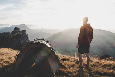 Rear view of man standing on mountain against sky