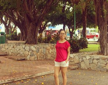 Portrait of smiling girl standing against tree