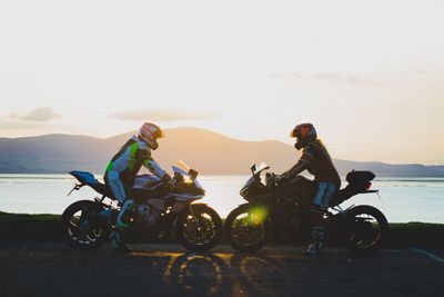 People riding motorcycle on sea against sky
