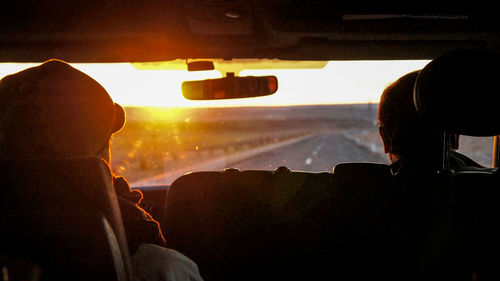 Rear view of men sitting in car during sunset