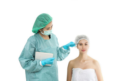 Surgeon examining patient against white background