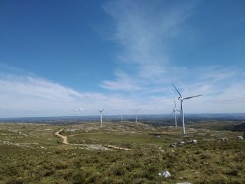 Wind turbines on field against sky