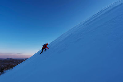 Person skiing on snowcapped mountain against blue sky