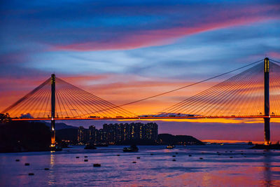 Suspension bridge over sea during sunset