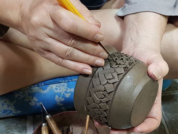 Close-up of person carving on earthenware