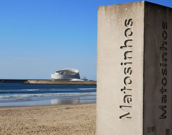 Information sign on beach against clear sky