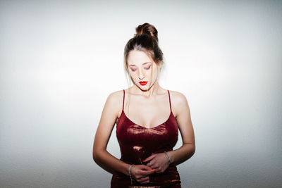 Portrait of young woman standing against wall