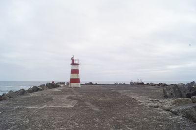 Lighthouse amidst sea and buildings against sky