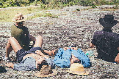 Full length of men sitting on rock