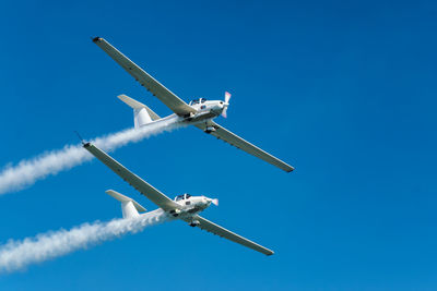 Low angle view of airplane flying against clear blue sky