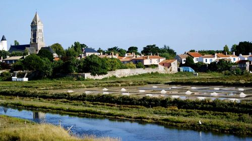 View of buildings by lake against clear sky