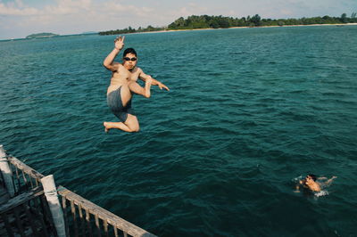 Full length of shirtless man jumping in sea