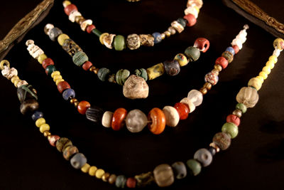 Close-up of beaded necklaces hanging over black background