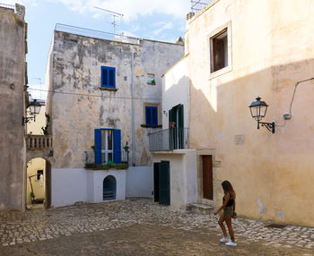 Side view of woman walking against old buildings in town