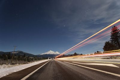 Light trails on road against sky at night