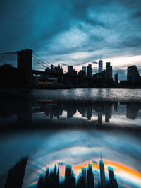 Buildings by river against sky in city