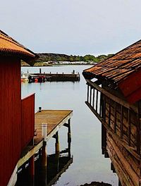 Pier on lake by buildings against sky